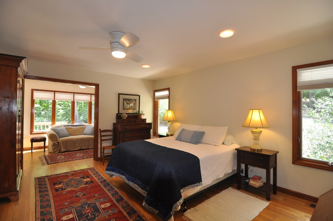 primary bedroom to sitting room the bedroom has hardwood floor and a ceiling fan.  there are french doors that open to the sitting room.