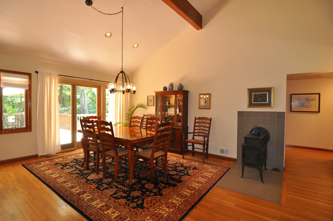 dining area the dining and living room flow into each other, and this area is 13 x 16.  there is a jotul, wood stove on a hearth between the rooms and there are pella sliding doors that go out to the back deck.  the floors are all hardwood and extend to the hall and other rooms on this side of the home.  the ceiling is vaulted over the dining area.