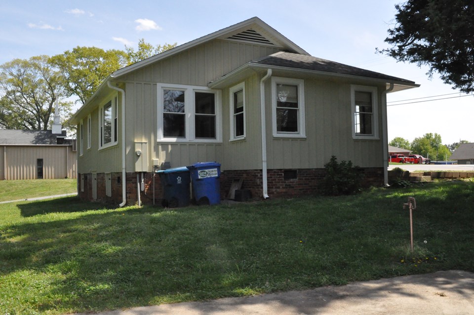 side view this view is of the left side with the extended area being the dining room. the cement pad shown in the photo was once used for the mobile home that was removed and remains on the lot for future use as a patio.